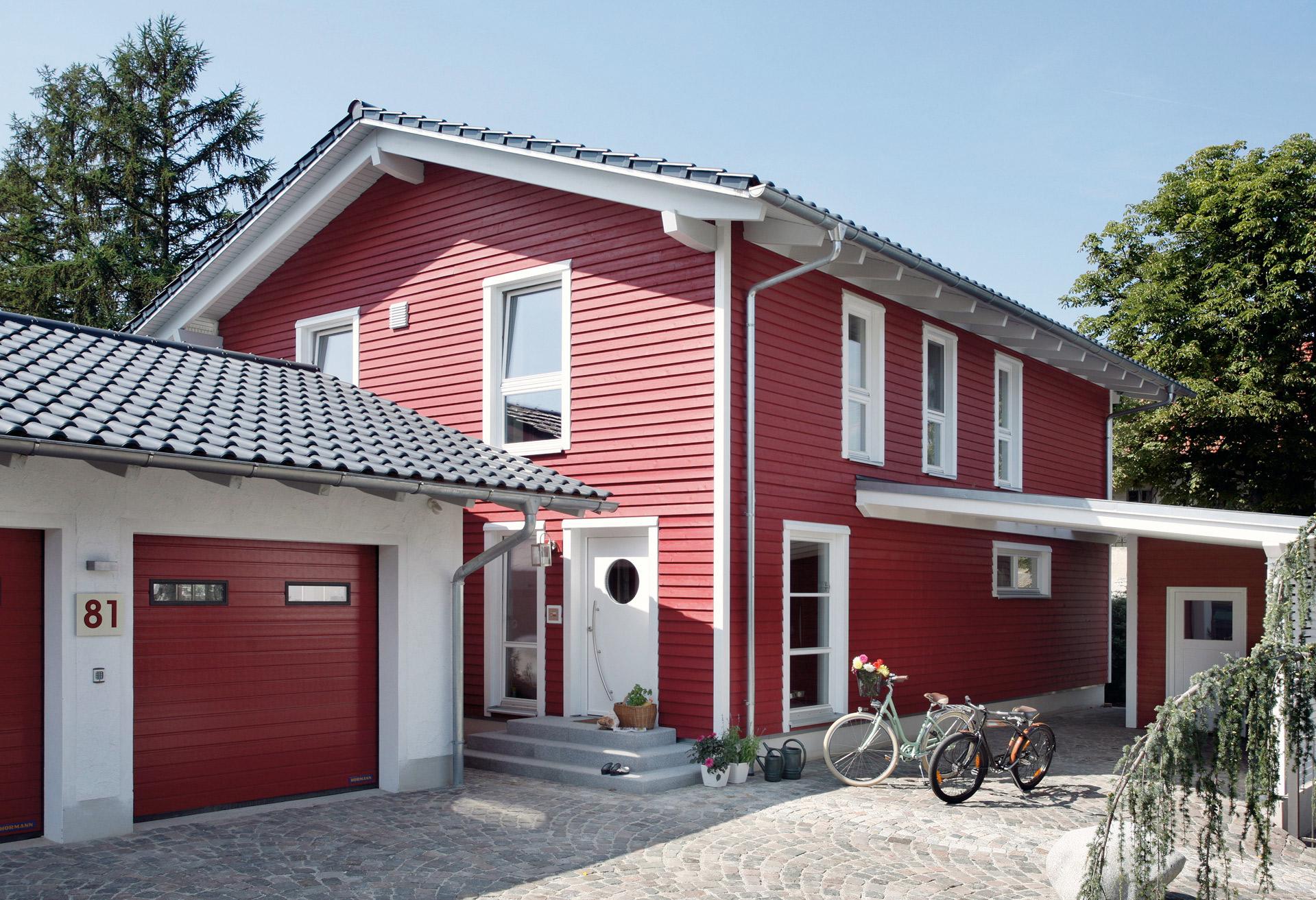 Prefabricated house with red wooden facade and double garage